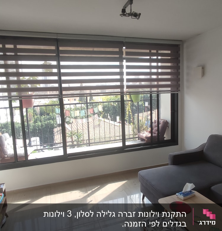 וילון גלילה חום על חלון גדול בסלון מואר